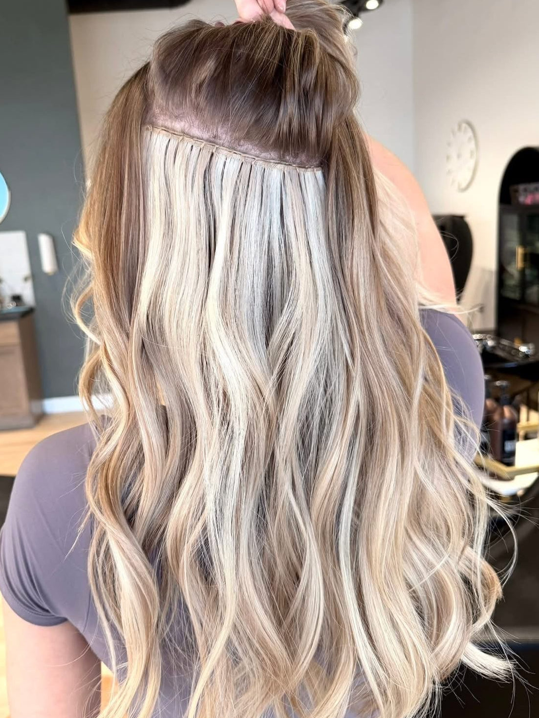 Person with long, wavy hair extensions in a salon setting
